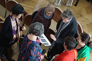 sechs Menschen unterhalten sich über die verkleinerte Klaviatur