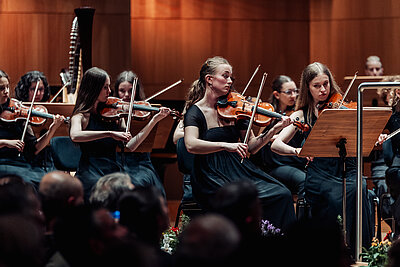 ein Teil des Orchesters spielt auf ihren Streichinstrumenten live auf einer Konzertbühne