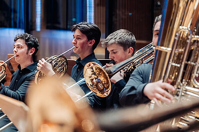 mehrere Studierende spielen auf ihren Blasinstrumenten live auf einer Konzertbühne
