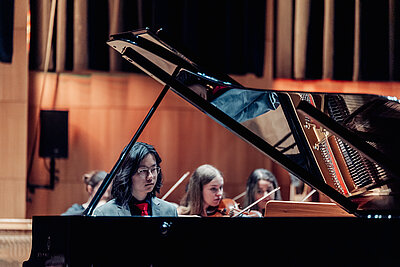 ein Pianist und ein Teil des Orchester des Tiroler Landeskonservatoriums spielt live auf einer Konzertbühne
