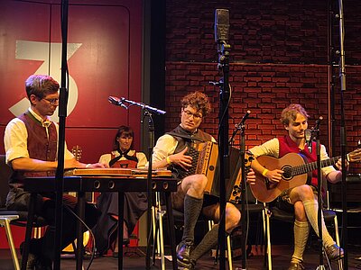 Studierende spielen Volksmusikinstrumente auf einer Konzertbühne