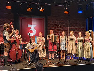Studierende spielen Volksmusikinstrumente auf einer Konzertbühne