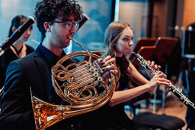 zwei Studierende spielen auf ihren Blasinstrumenten live auf einer Konzertbühne