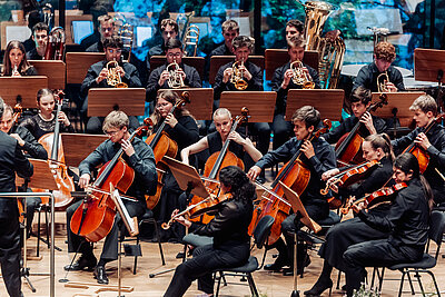 das Orchester des Tiroler Landeskonservatoriums spielt live auf einer Konzertbühne mit Publikum in den ersten Reihen