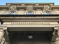 Fasade des Tiroler Landeskonservatoriums mit Schriftzug nach oben fotografiert, blauer Himmel im Hintergrund