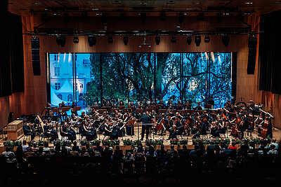 das Orchester des Tiroler Landeskonservatoriums spielt live auf einer Konzertbühne mit Publikum in den ersten Reihen
