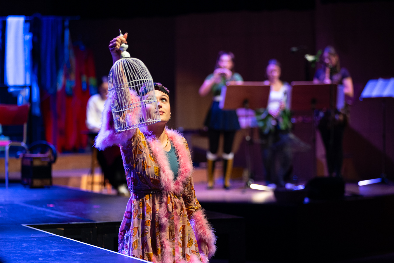 Studierende in bunten Kostümen performen live auf der Bühne 