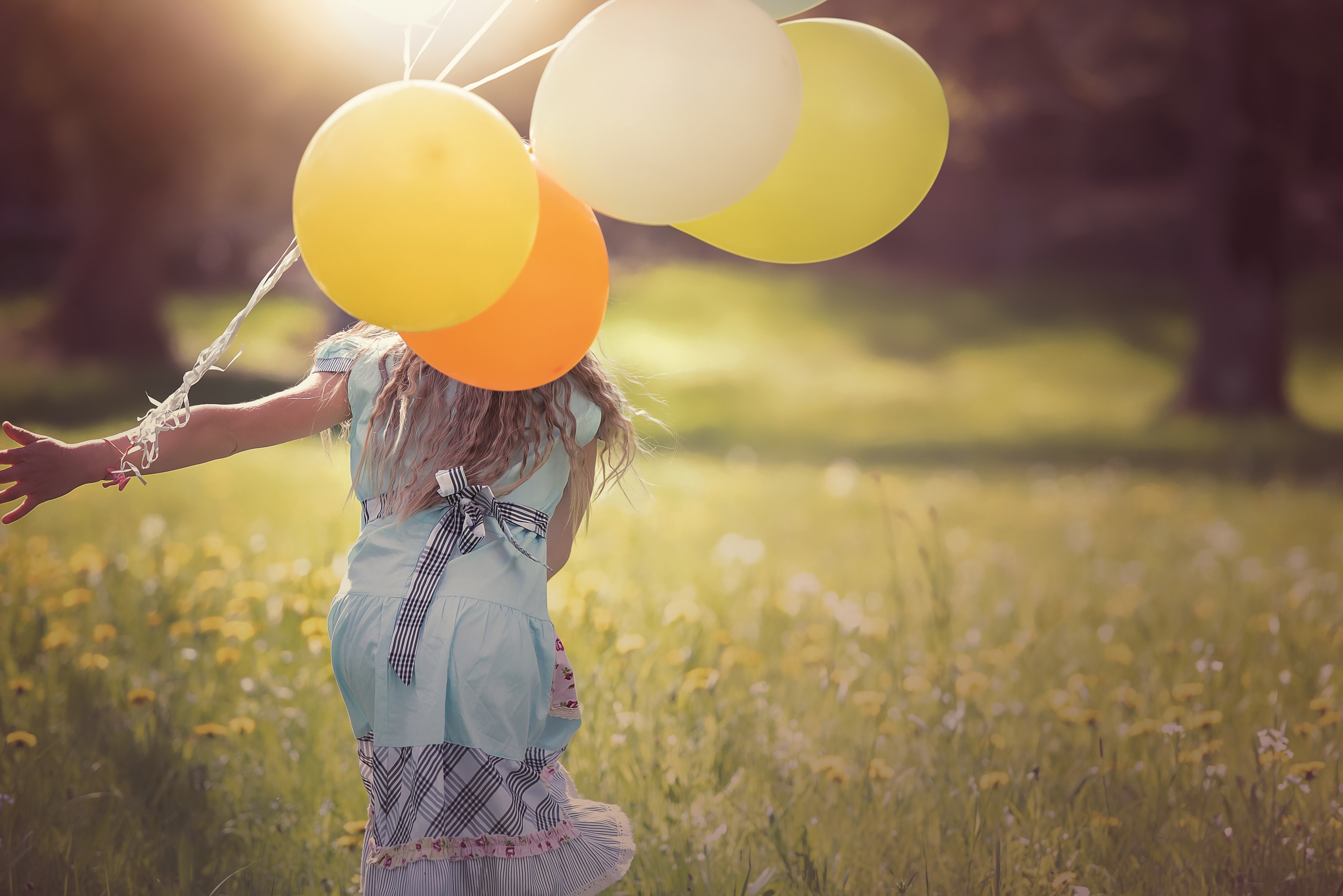Mädchen mit bunten Luftballons auf einer Sommerwiese
